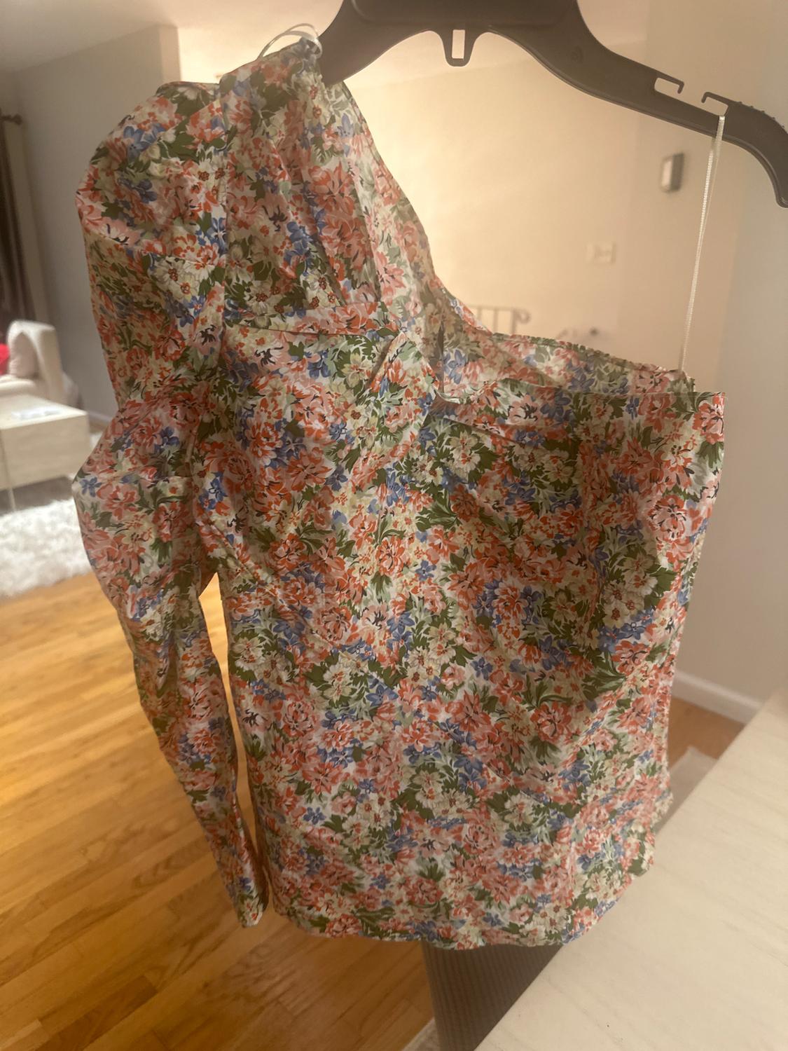 Detail of a shirt with a floral print in shades of green, pink, and blue, side view.