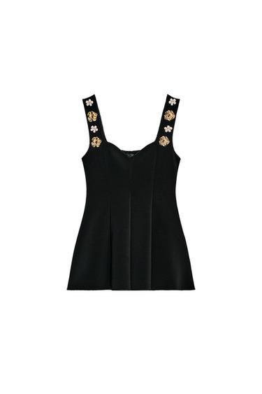 Front view of a black top with a sweetheart neckline, wide jeweled straps, and a peplum hem.