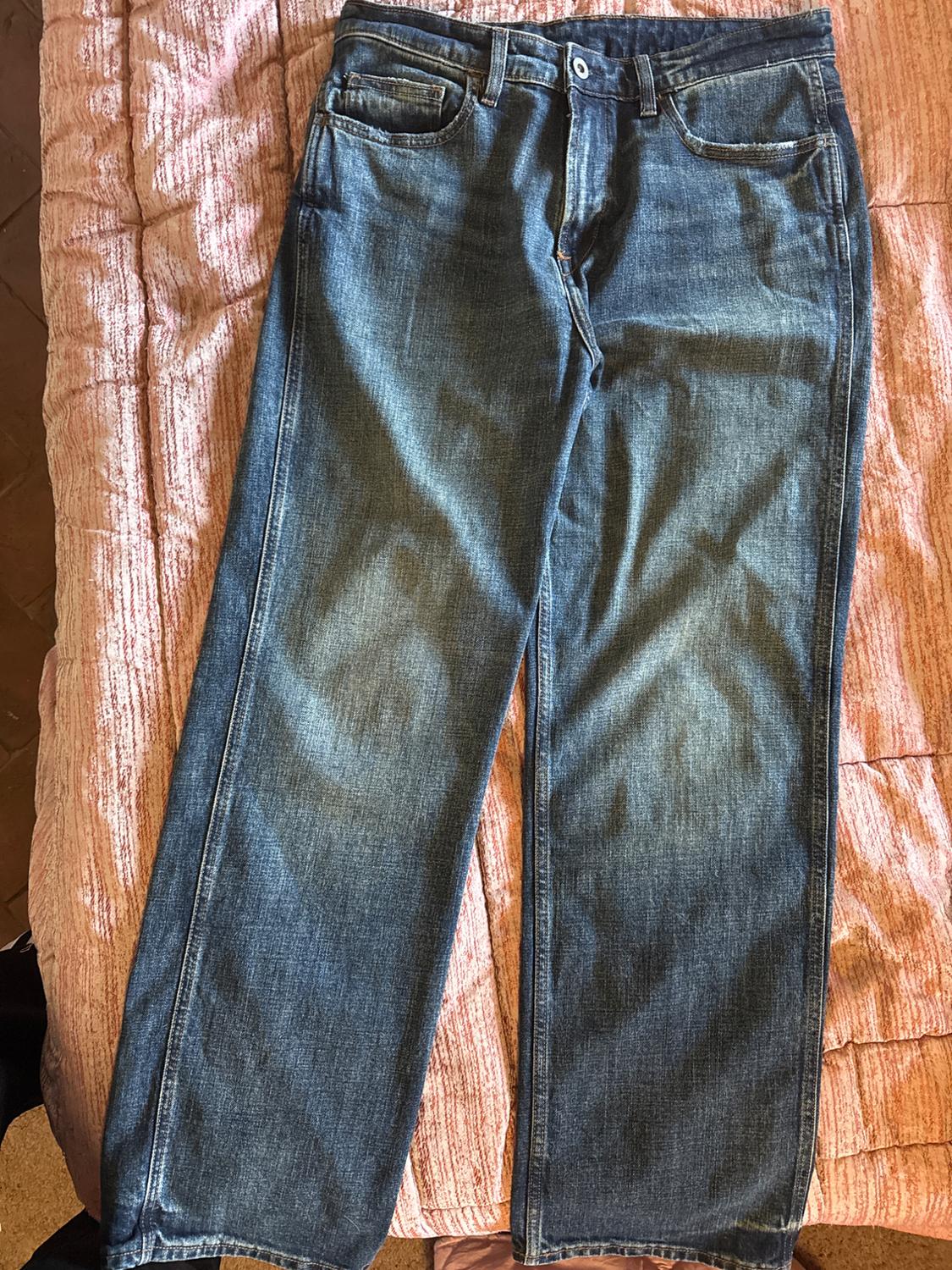 Blue straight-cut jeans on a textured pink bedspread. The jeans have front and back pockets.