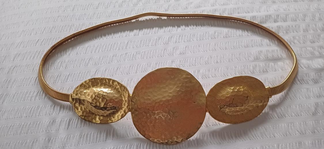 Gold belt with three textured round plates on a white background. Elegant and modern design.
