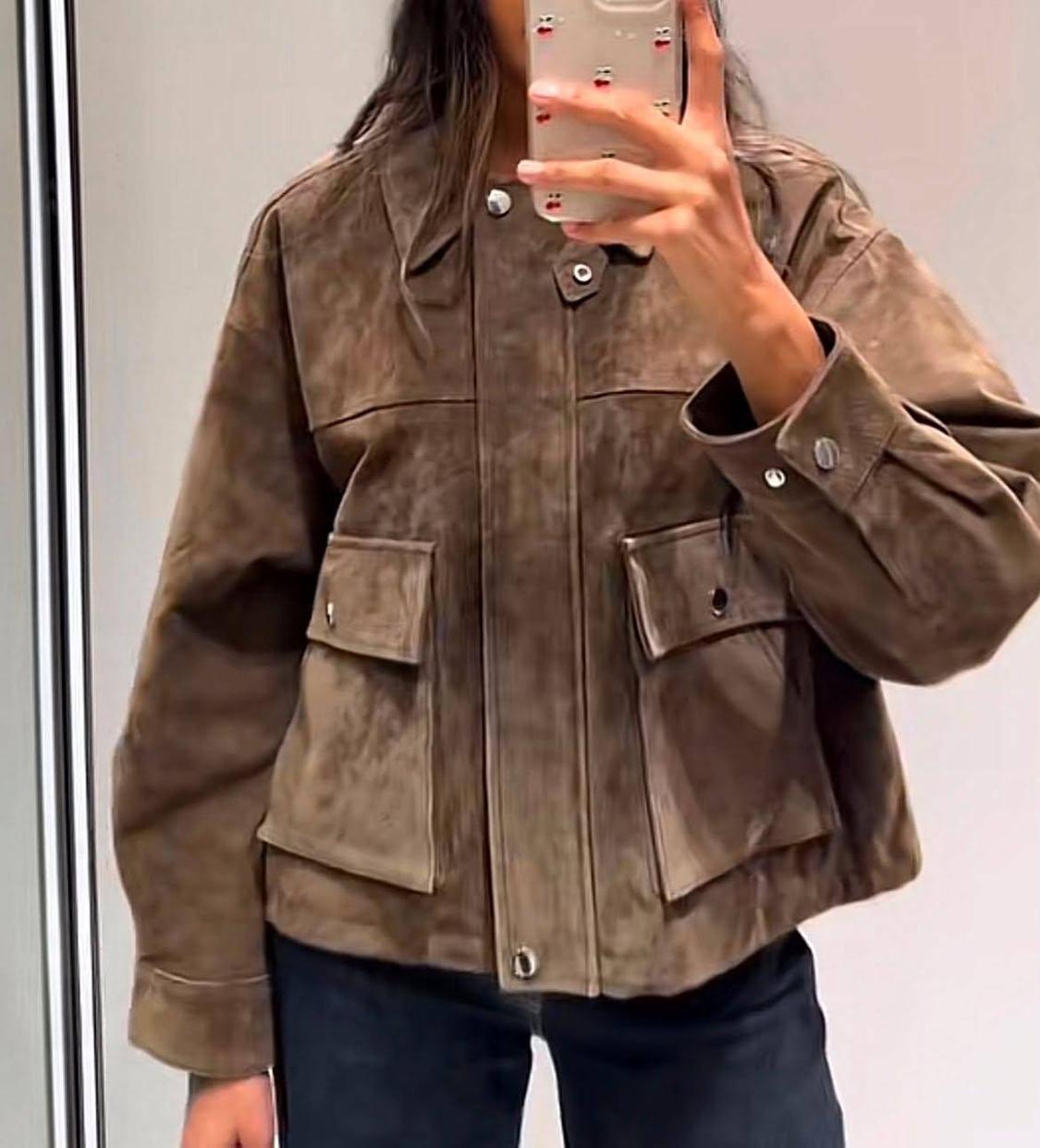 Mirror selfie of a person wearing a brown jacket with flap pockets and buttons, paired with dark trousers.