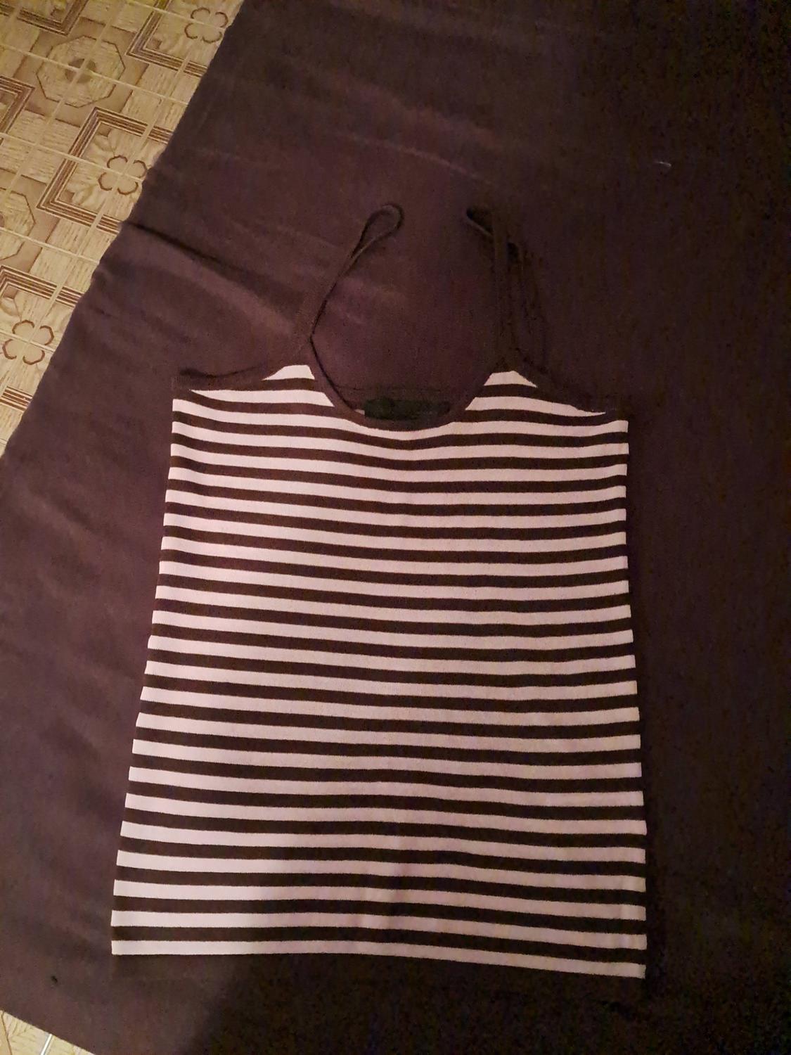 Spaghetti-strap top with horizontal stripes on dark fabric. A tiled floor can be seen in the top-left corner.