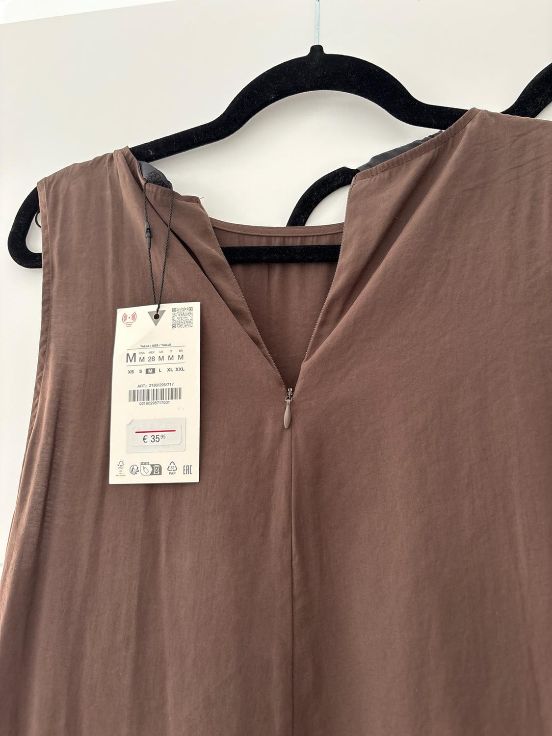 Brown garment on a black hanger with a back zip and label. Text: SIZE / SIZE / SIZE M, ART.: 2180/295/717, €35.95.