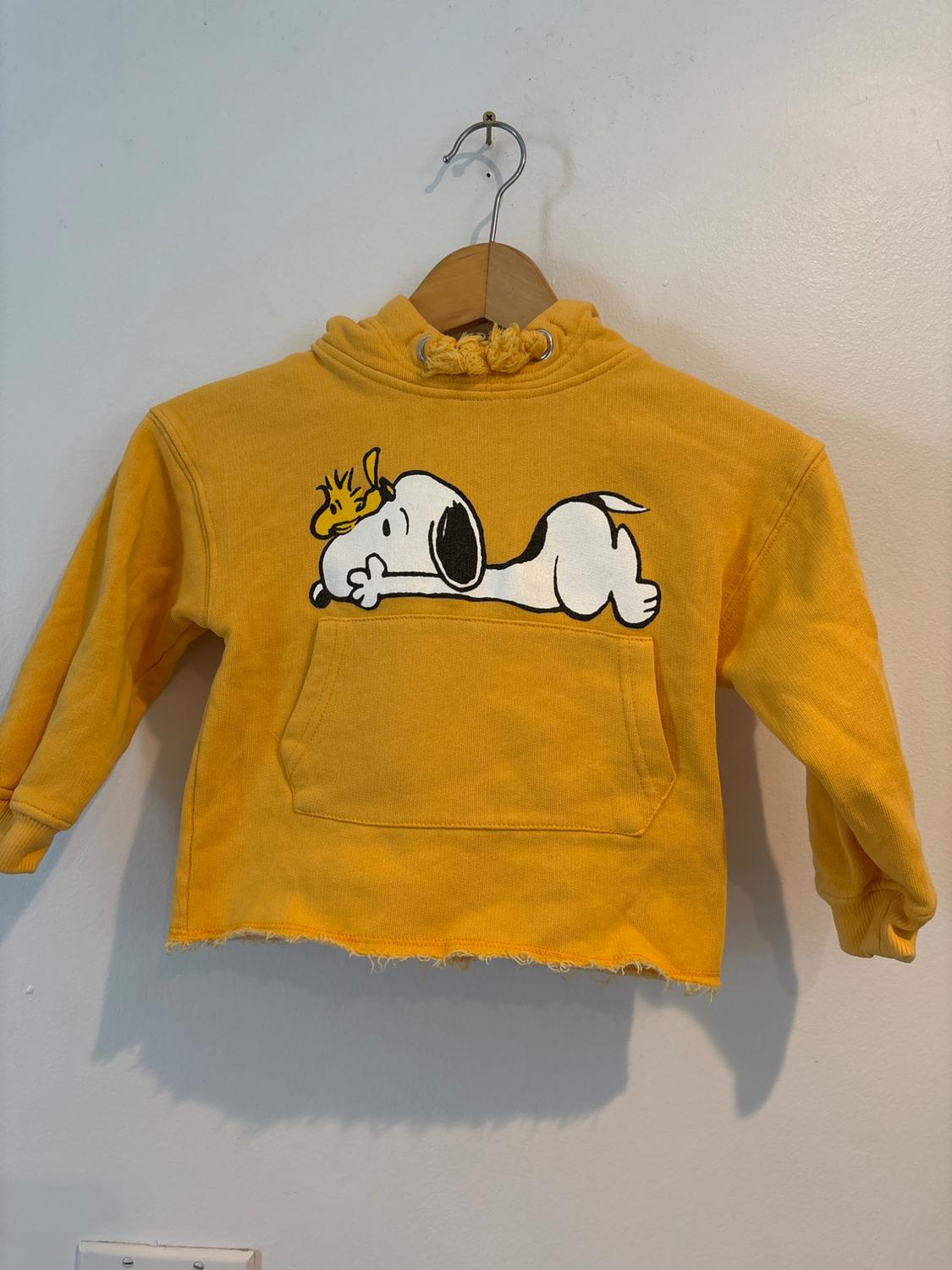 Front view of yellow hooded sweatshirt with Snoopy and Woodstock print, front pocket, and frayed hem.