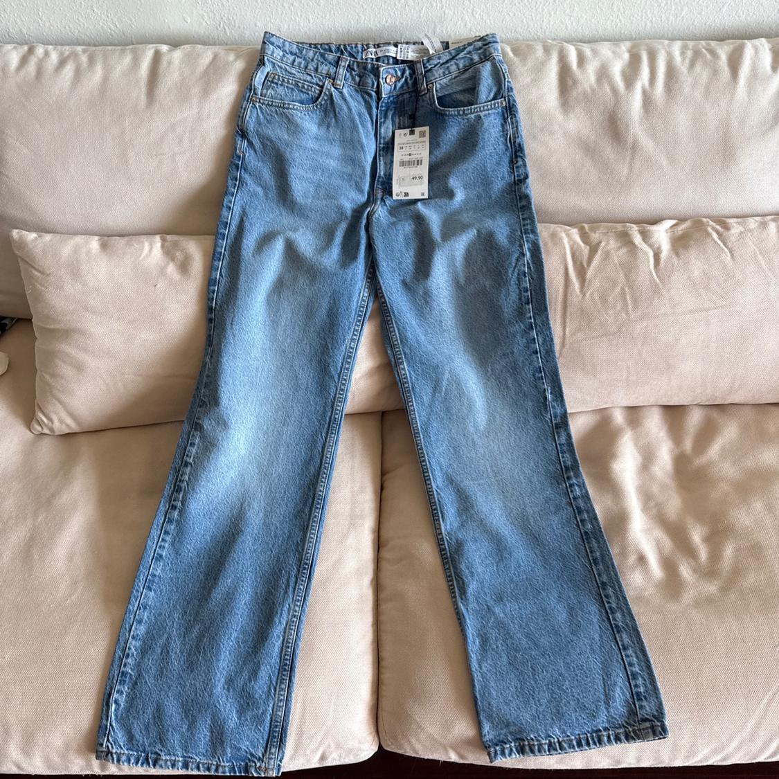 Blue jeans with a hang tag, placed on a beige sofa.