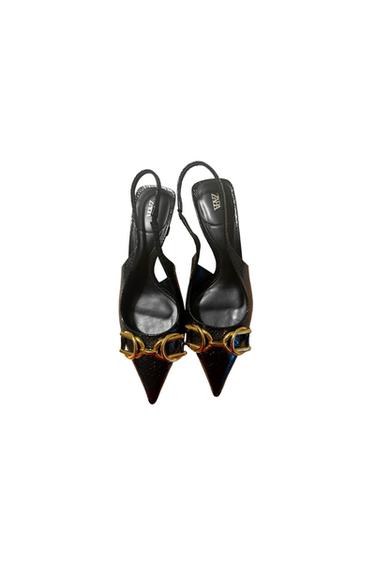 Black high heels with pointed toes and gold buckles. White background. Visible text: "ZARA" on the insole.