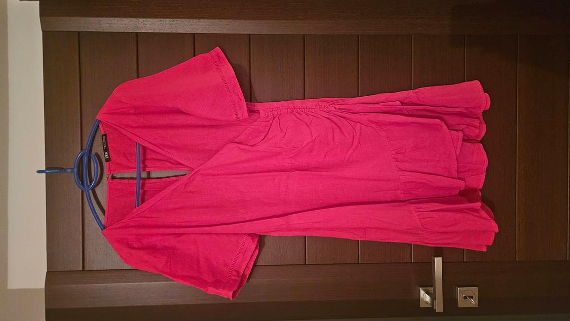 Red dress hanging on a blue hanger over a dark wooden door.