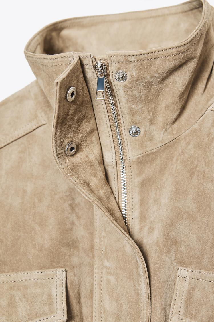 "Lapel collar detail and zip of taupe brown jacket, with visible snap fasteners and flap pockets."