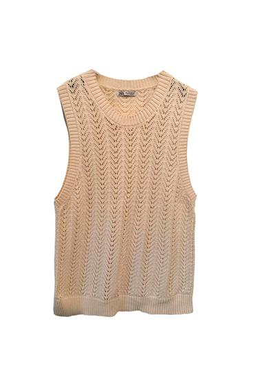 Beige knitted sleeveless gilet with openwork zigzag design, round neck, and visible inner label. White background.