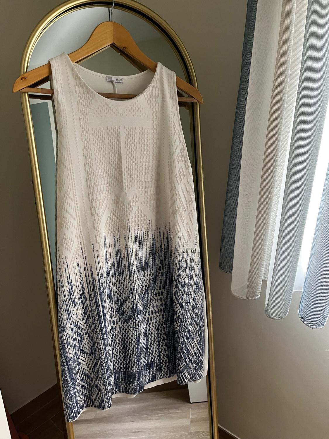 Front view of a sleeveless dress with a geometric print in white and blue tones.
