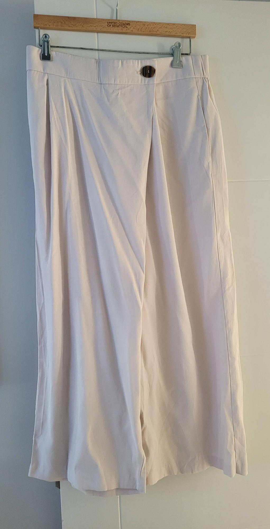 Beige trousers hanging on a wooden hanger with the "United Colors of Benetton" brand visible at the top.