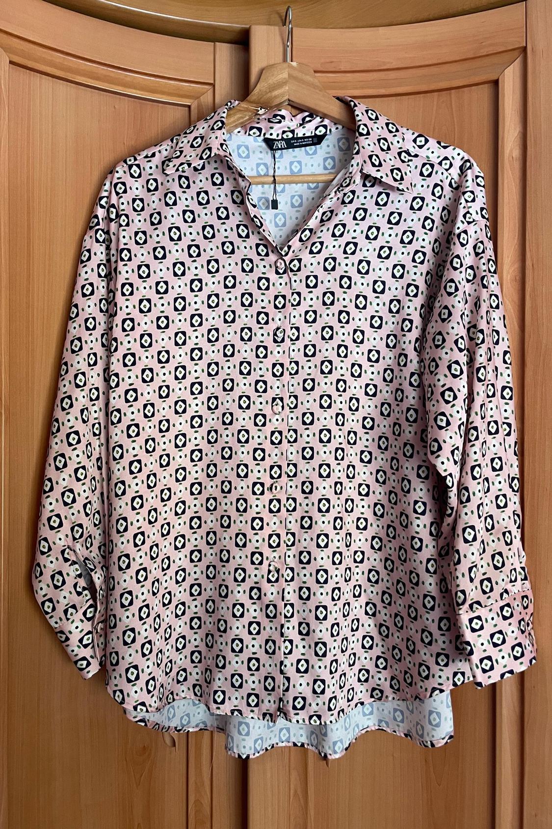 Front view of a printed shirt with a geometric pattern in pink and black tones, with a collar and buttons.