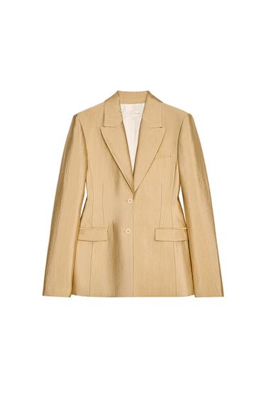 Front view of a beige blazer with lapels and two buttons, flap pockets.
