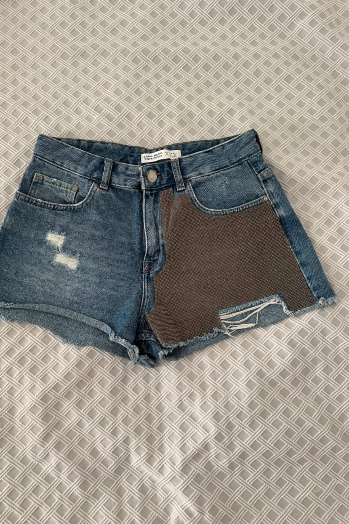Front view of blue denim shorts with patches and front pockets.