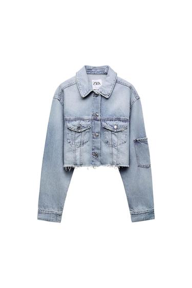 Light blue denim cropped jacket with front pockets and frayed hem detail. Visible tag with "ZARA" text.