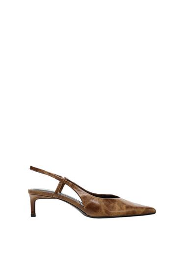 Brown low-heeled shoe with a pointed toe design and back strap, on a white background.