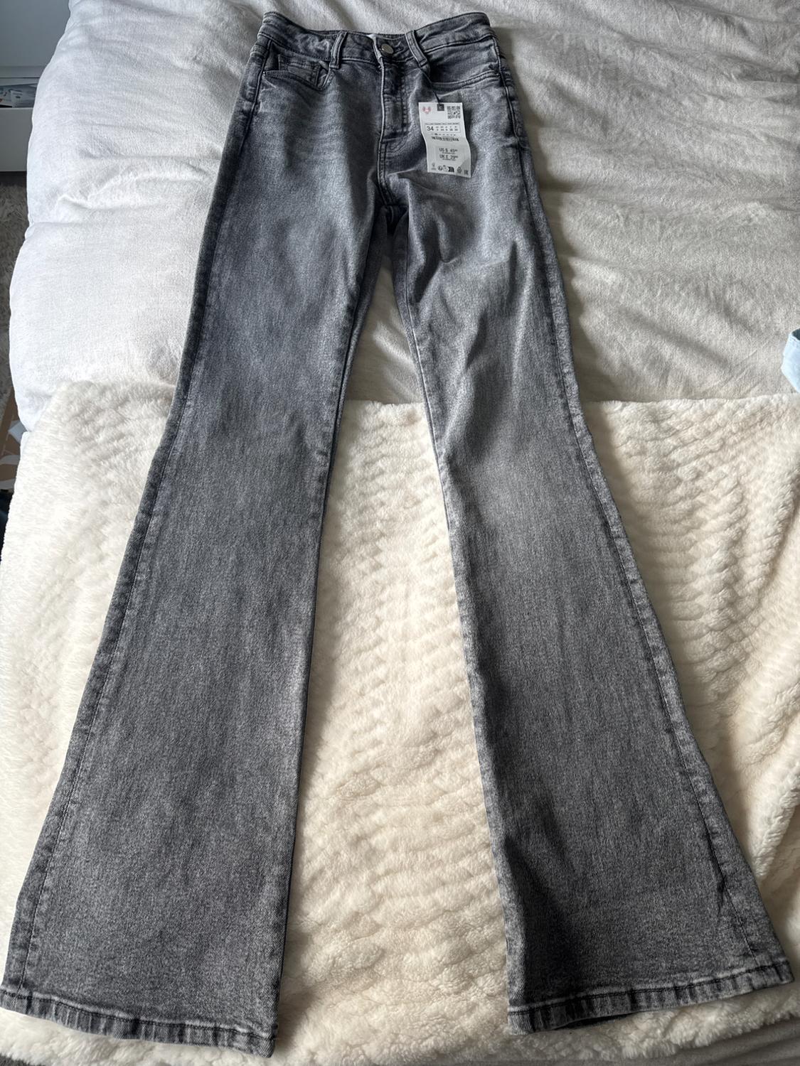 Front view of flared gray pants with front pockets and visible tag.