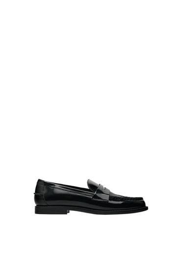 Side view of a black loafer shoe with buckle detail on the top.
