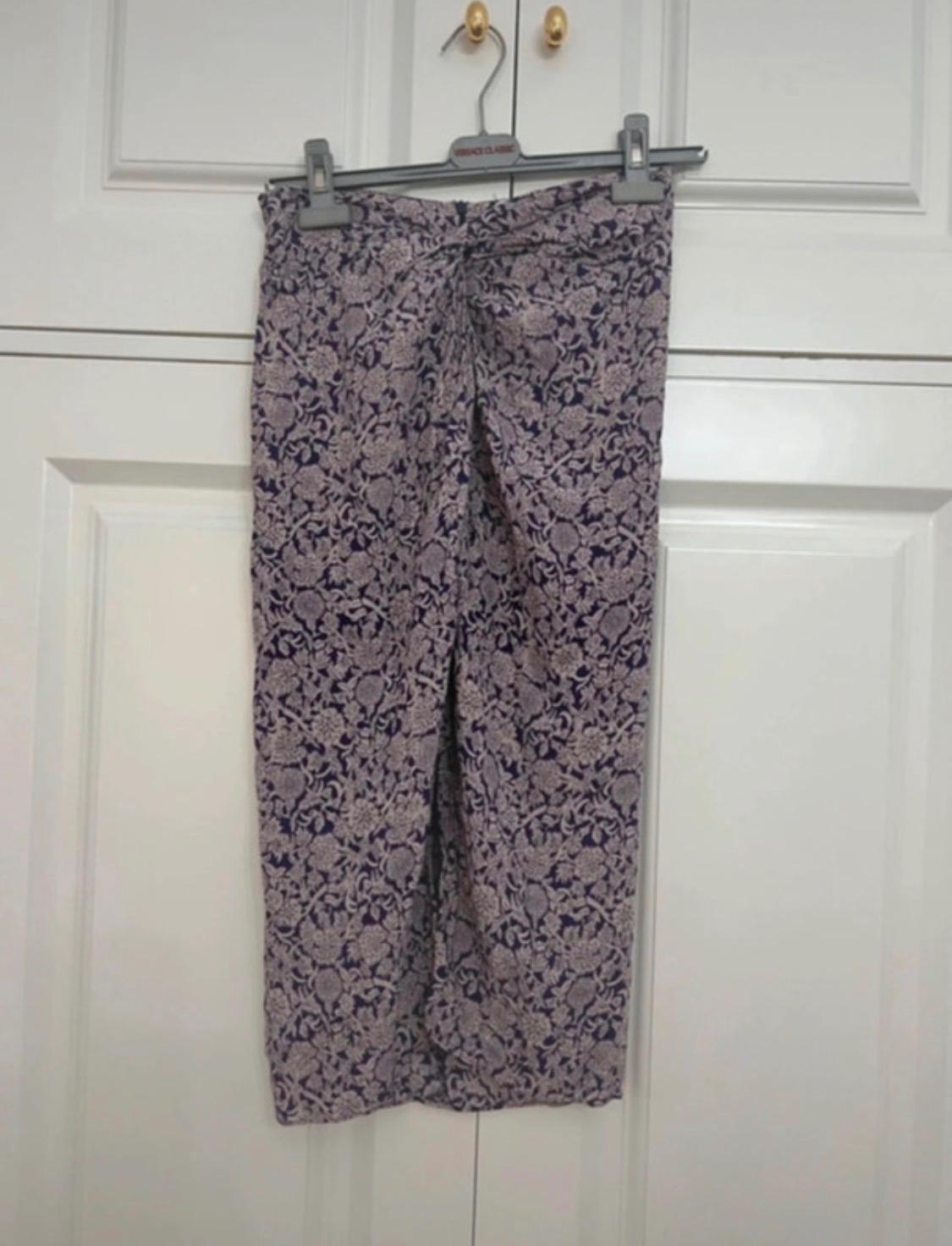 Floral print skirt hanging on a white door. The hanger features the text VERSACE CLASSIC. Casual and homely style.