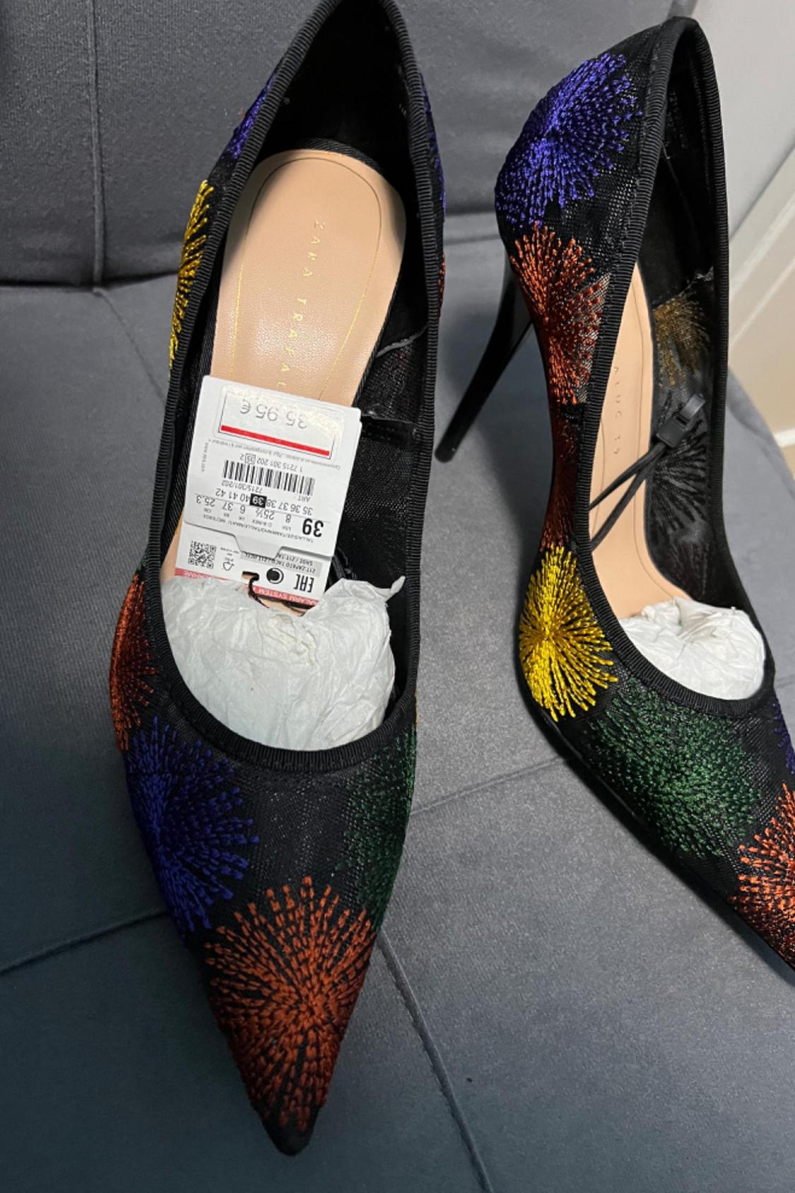 Detail of embroidered high-heeled shoes with a firework design in red, blue, and green colours.
