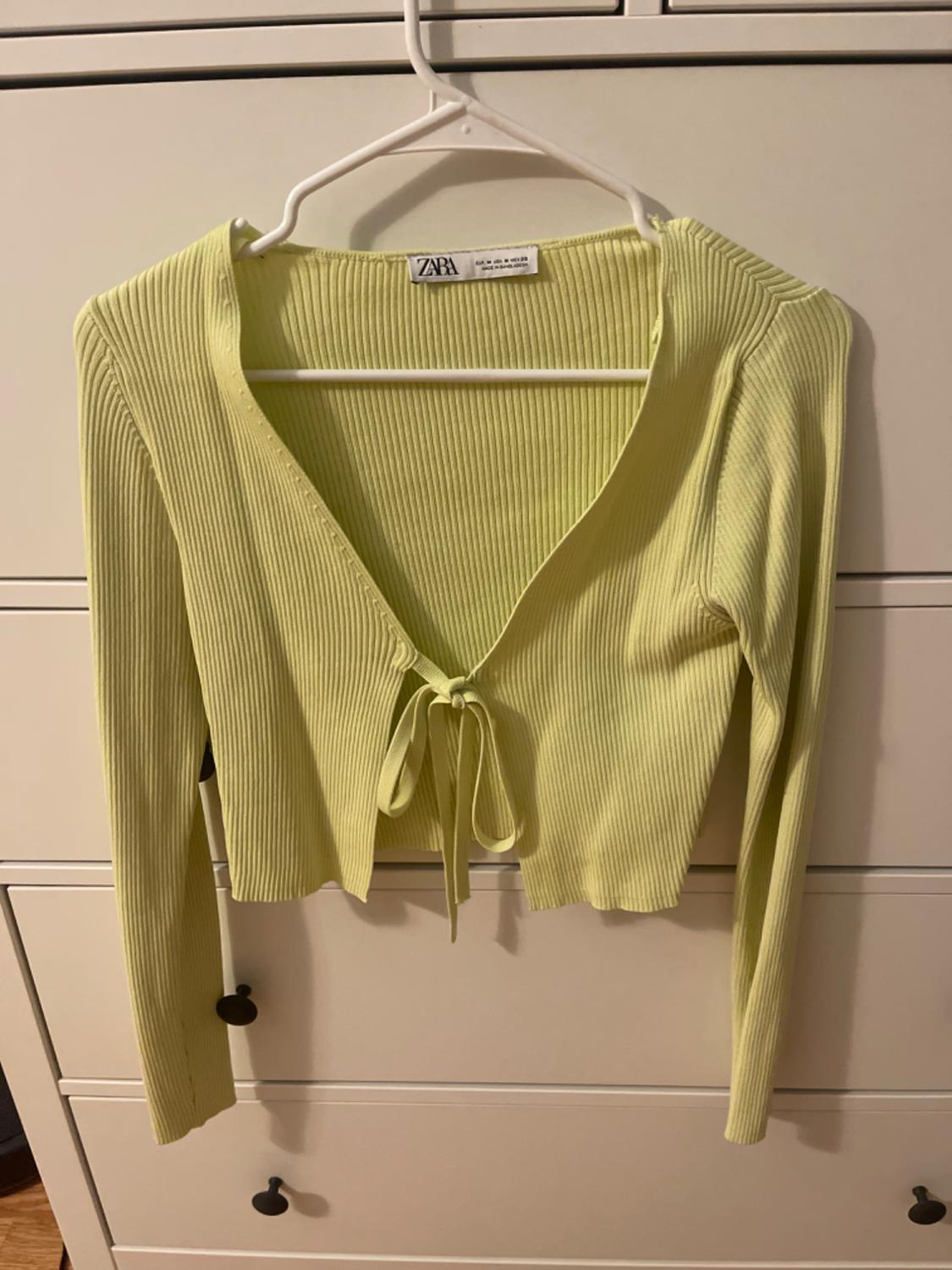 Front view of a light yellow ribbed cardigan with a bow at the front and long sleeves.