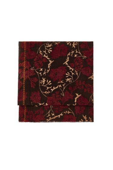 Front view of a brown scarf with a red and beige floral print, frayed edges.
