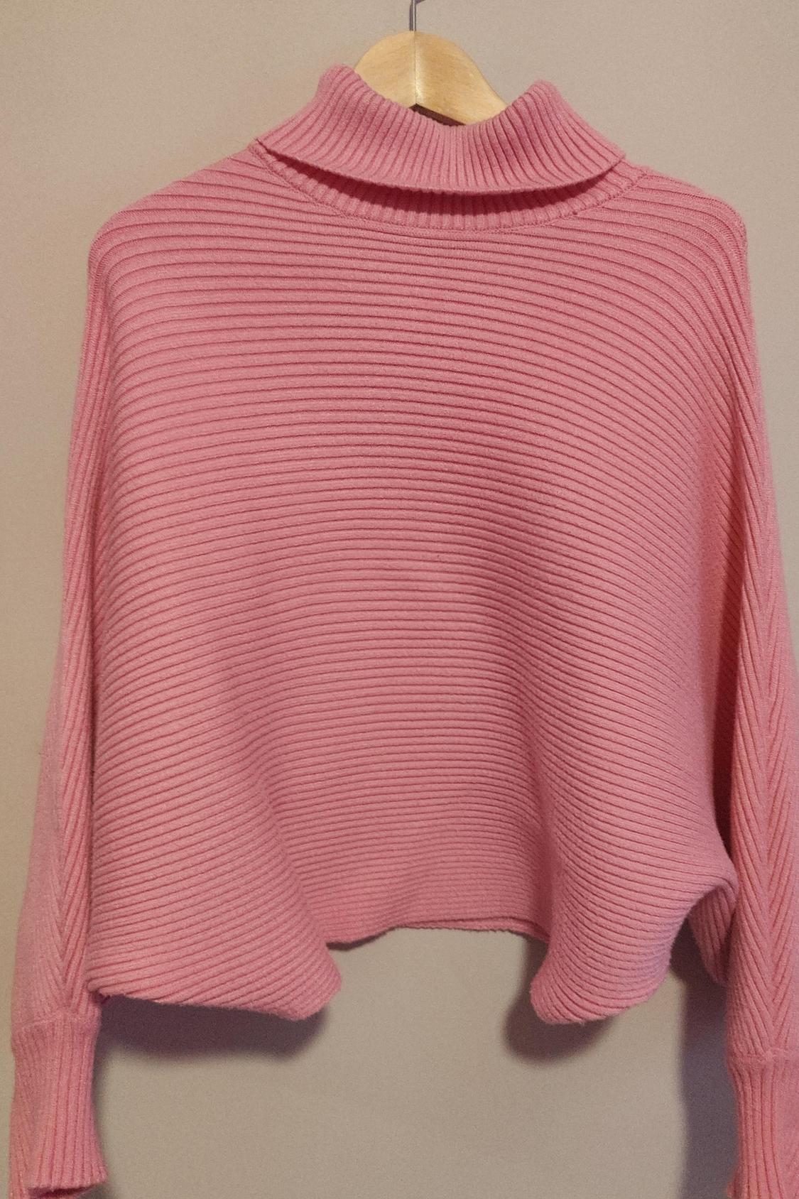 Front view of pink high-neck sweater with ribbed texture.