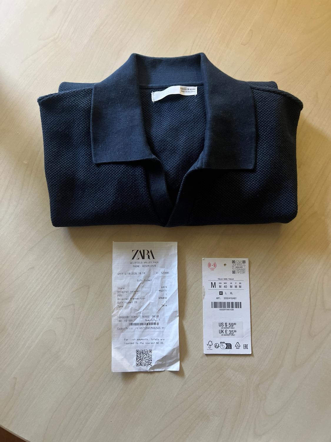 Textured navy blue polo shirt folded on wood. Includes a receipt with the text “ZARA Gift Ticket” and a tag with the text “US $59.90.”