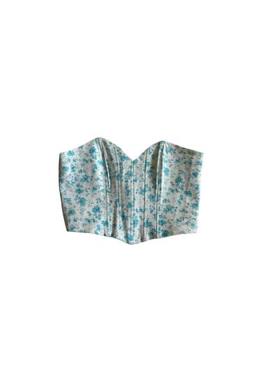 White corset with blue floral print on a white background. Strapless design with ribbed structure.