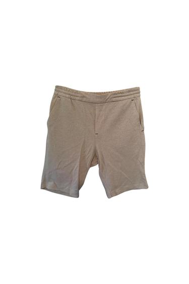 Front view of beige shorts with side pockets and elasticated waistband.