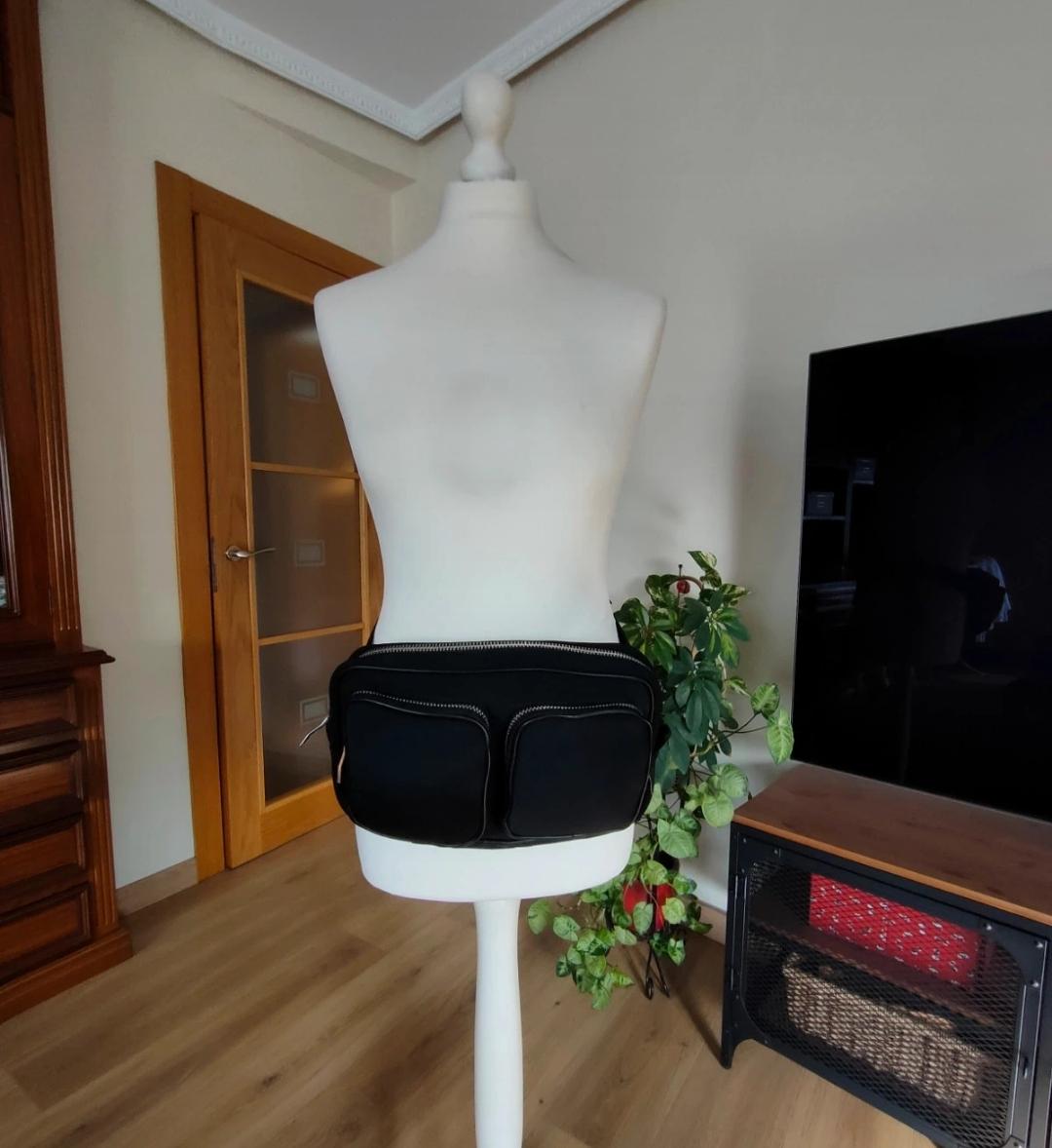 Front view of a black bum bag with two front pockets and visible zips.