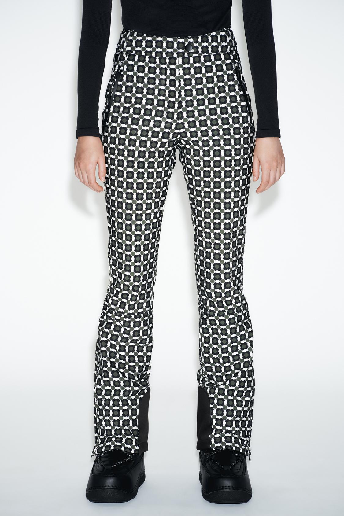 Srednji posnetek črno-belih hlač z vzorcem, s stranskimi žepi in sprednjim zapenjanjem.