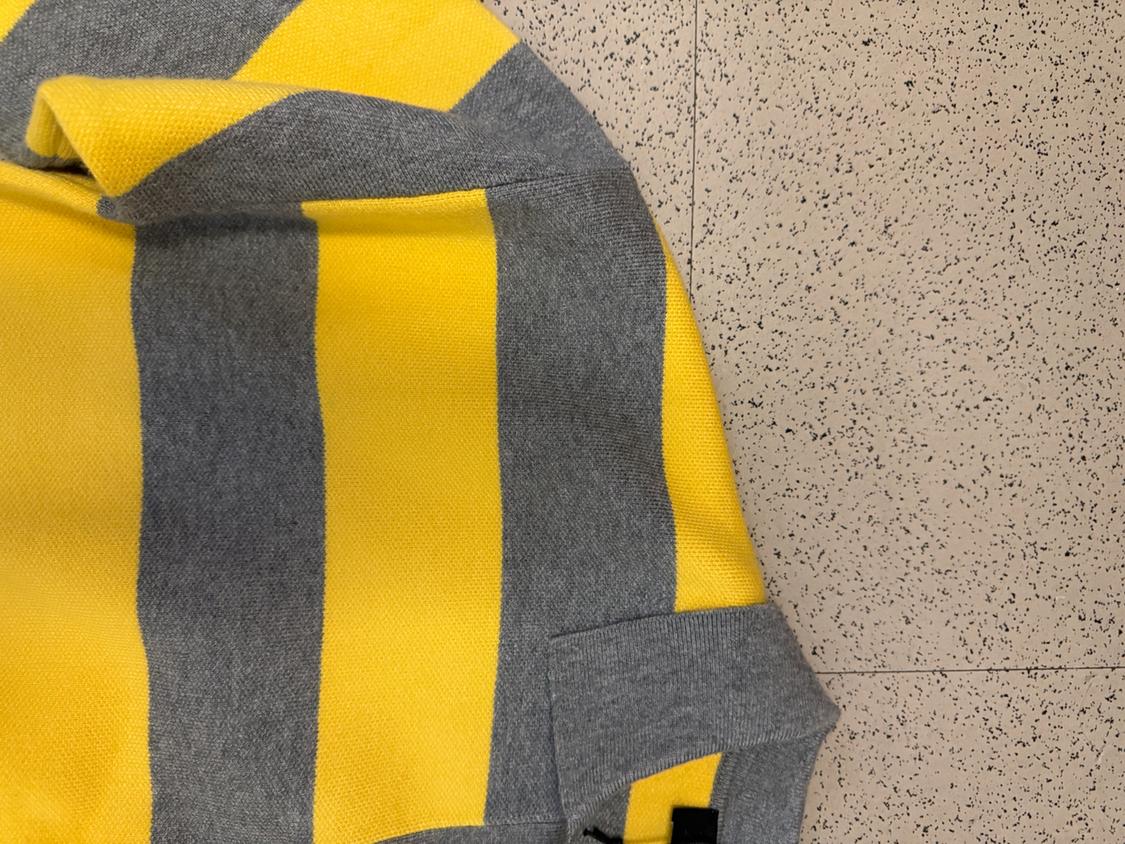 Gray and yellow striped sweater on a light floor background with a mottled texture.