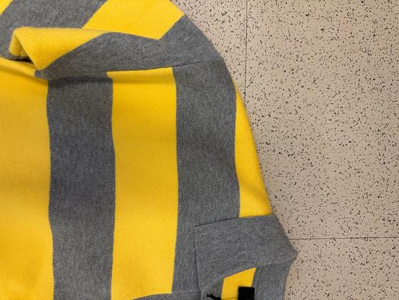 Gray and yellow striped sweater on a light floor background with a mottled texture.