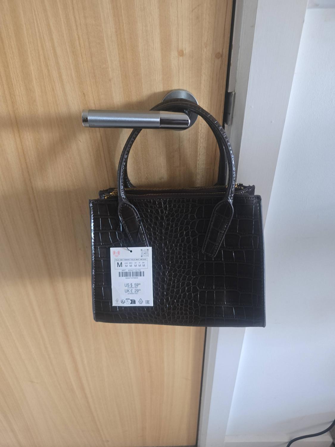 Dark brown crocodile-textured handbag hanging on a door handle. Text: US $ 59.90 UK £ 29.99