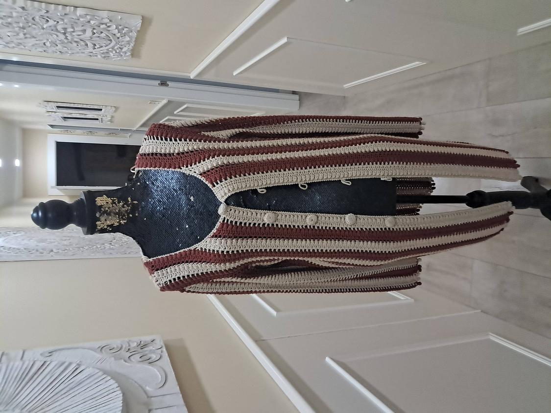 Mannequin in a brown and beige striped coat in a hallway with white wall decor and light tiled flooring.