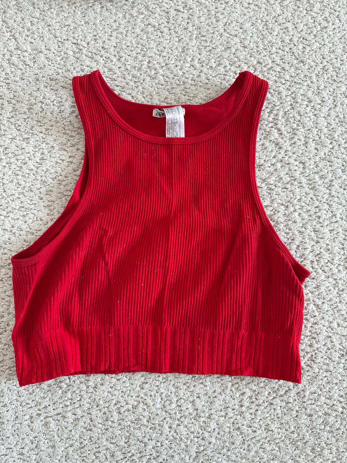Red ribbed crop top on a gray carpet, with visible label on the neck.