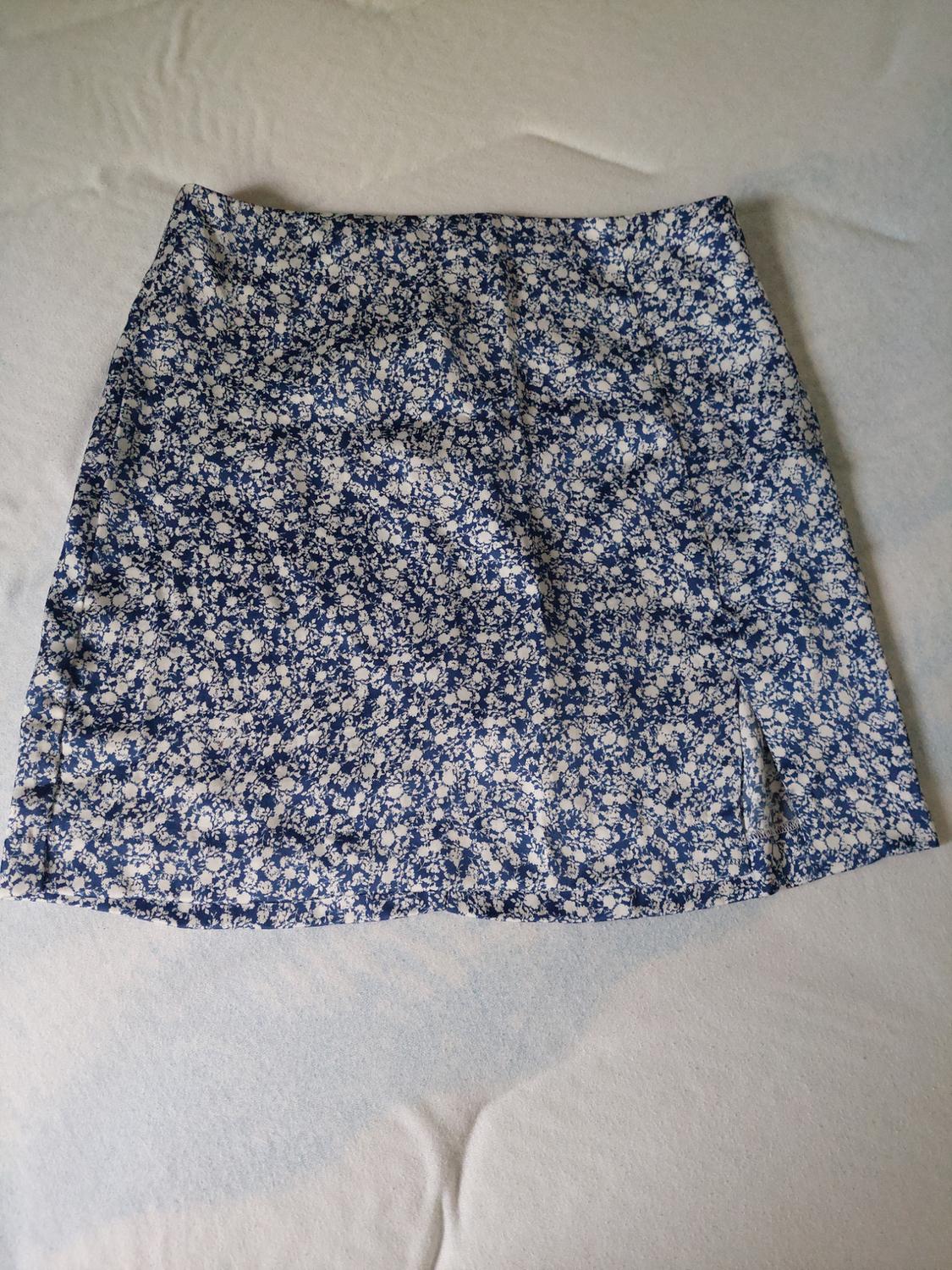Short skirt with blue and white floral print on a light background, placed on a smooth surface.