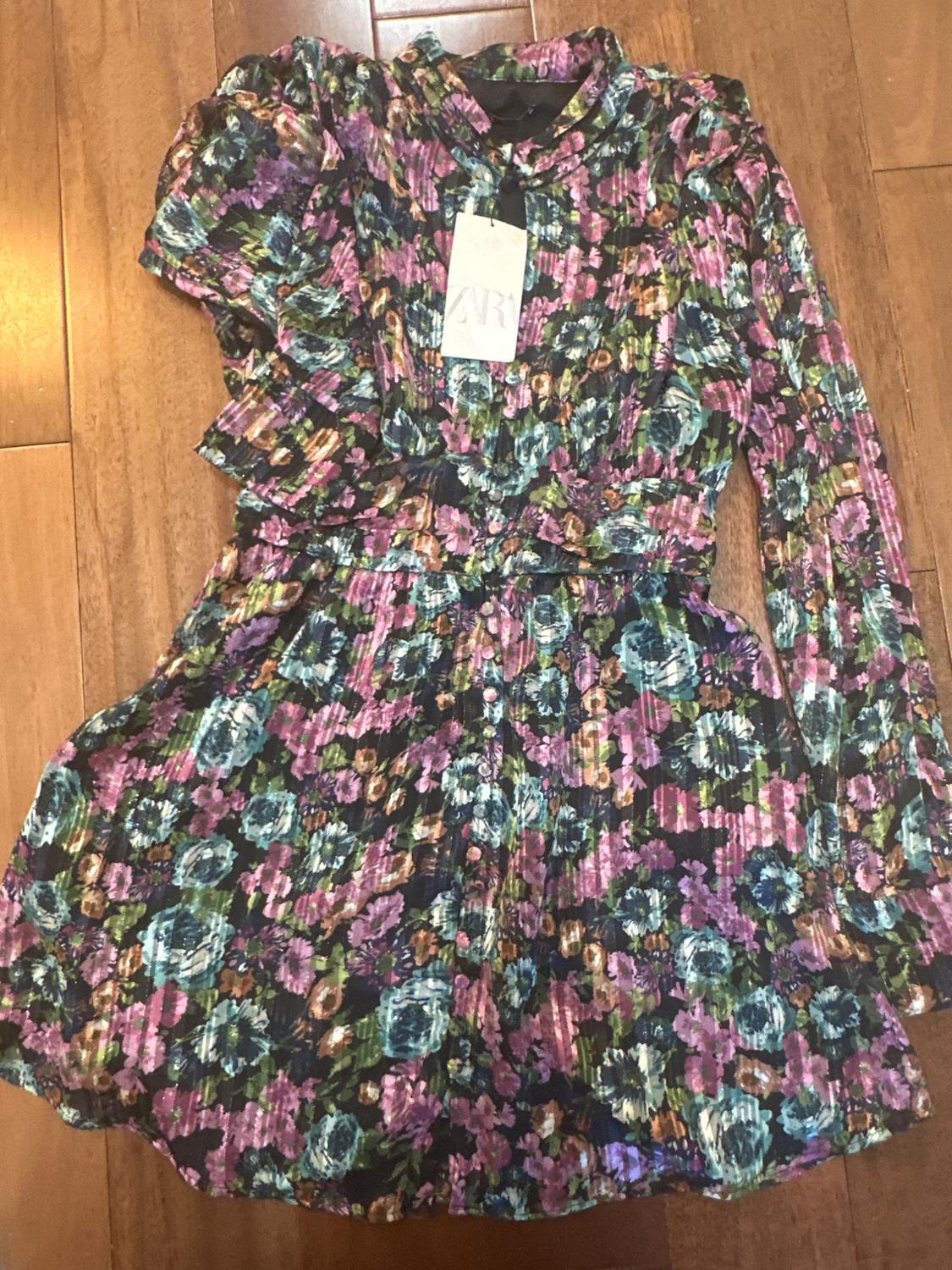 Multicolor floral dress on wooden floor, with visible label that reads "ZARA".