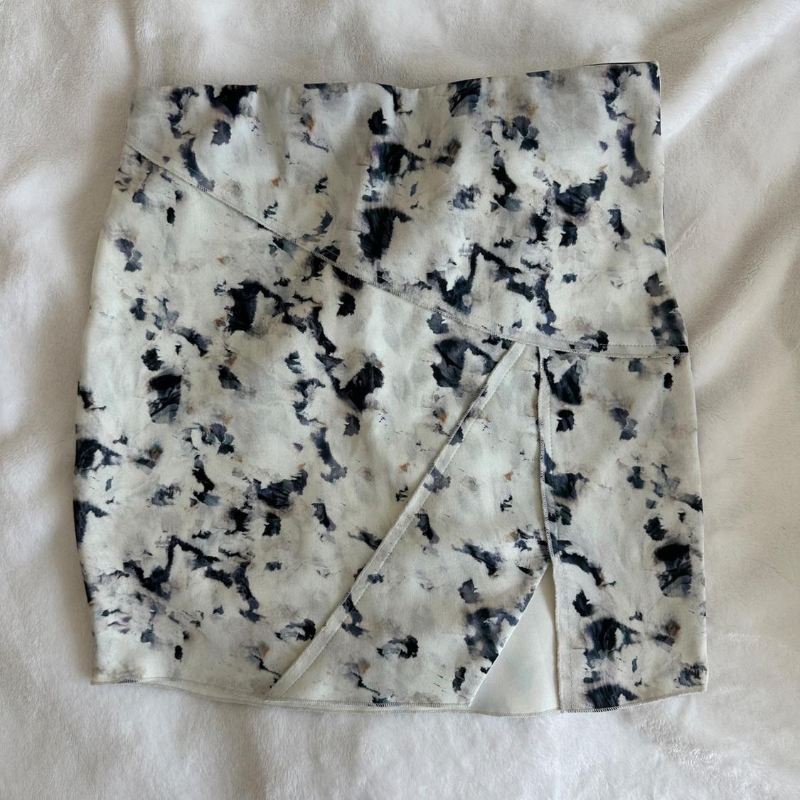 Short skirt with a black and white abstract print on a white background, placed on a white fabric surface.