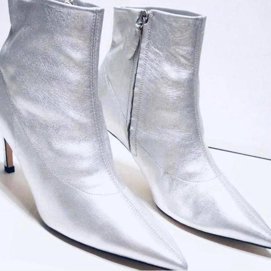 Silver high-heeled, pointed-toe ankle boots with side zip fastening, on a white background.