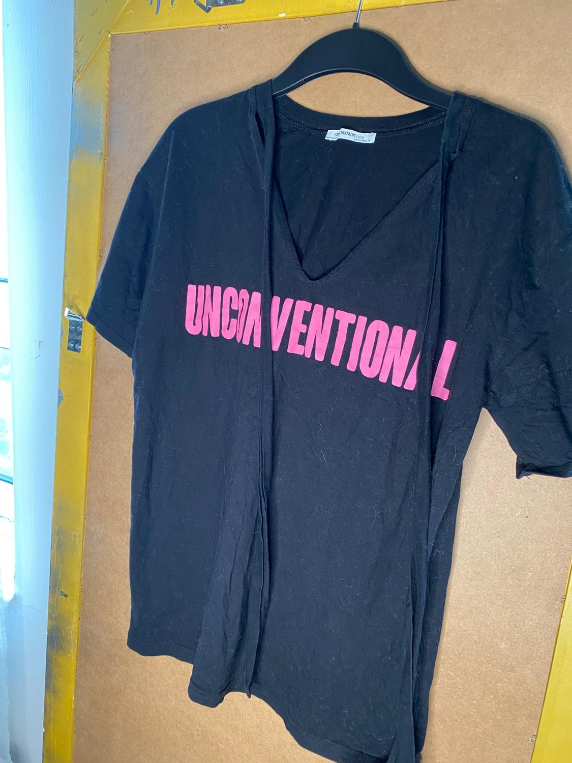 Front view of a black t-shirt with 'UNCONVENTIONAL' text in pink, V-neck.