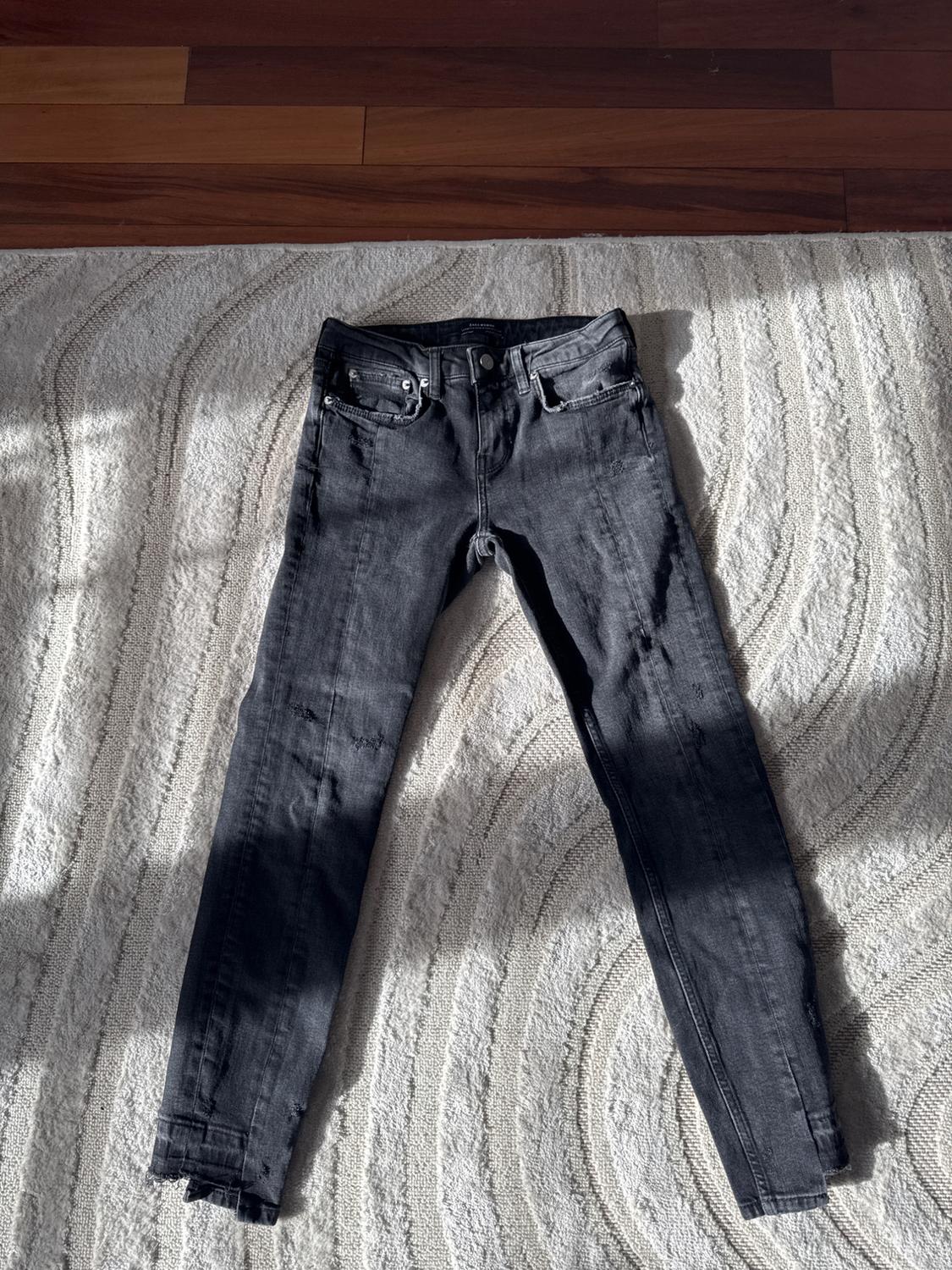 Front view of black slim-fit trousers with front and back pockets.