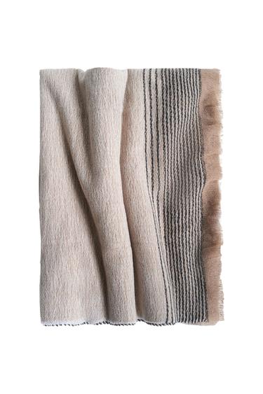 Front view of beige blanket with black stripes on the edge