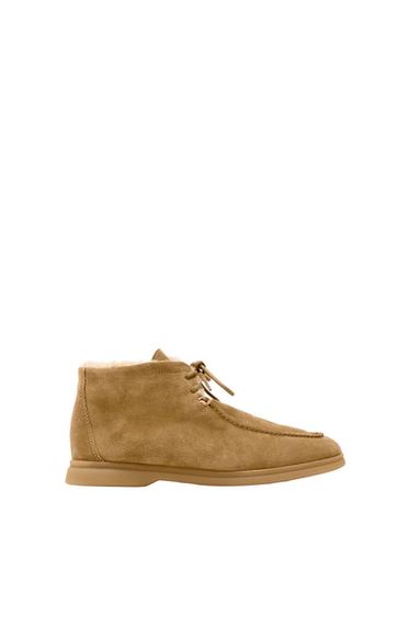 Beige suede boot with laces, side view on a white background. Simple and modern design.