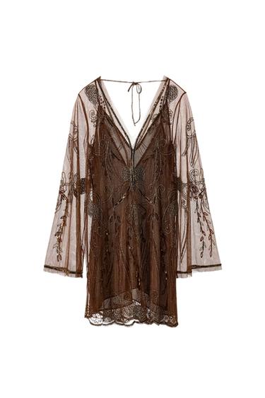 Front view of a short brown dress with a V-neckline, long sleeves, and beaded embroidery. Tie detail at the back.