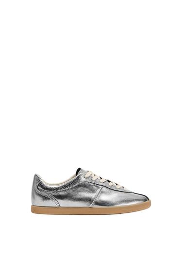 Metallic silver trainers with white laces and a brown sole, photographed from the side against a white background.