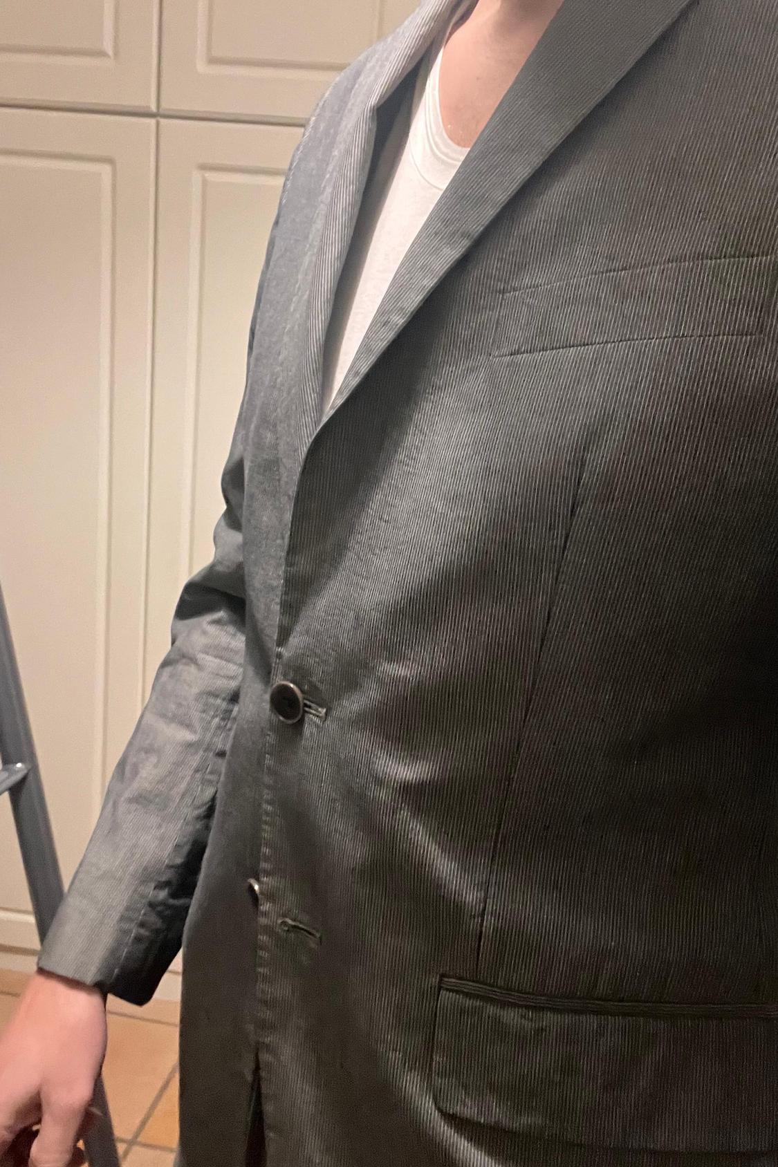 Close-up of grey jacket with lapels, front buttons and chest pocket.