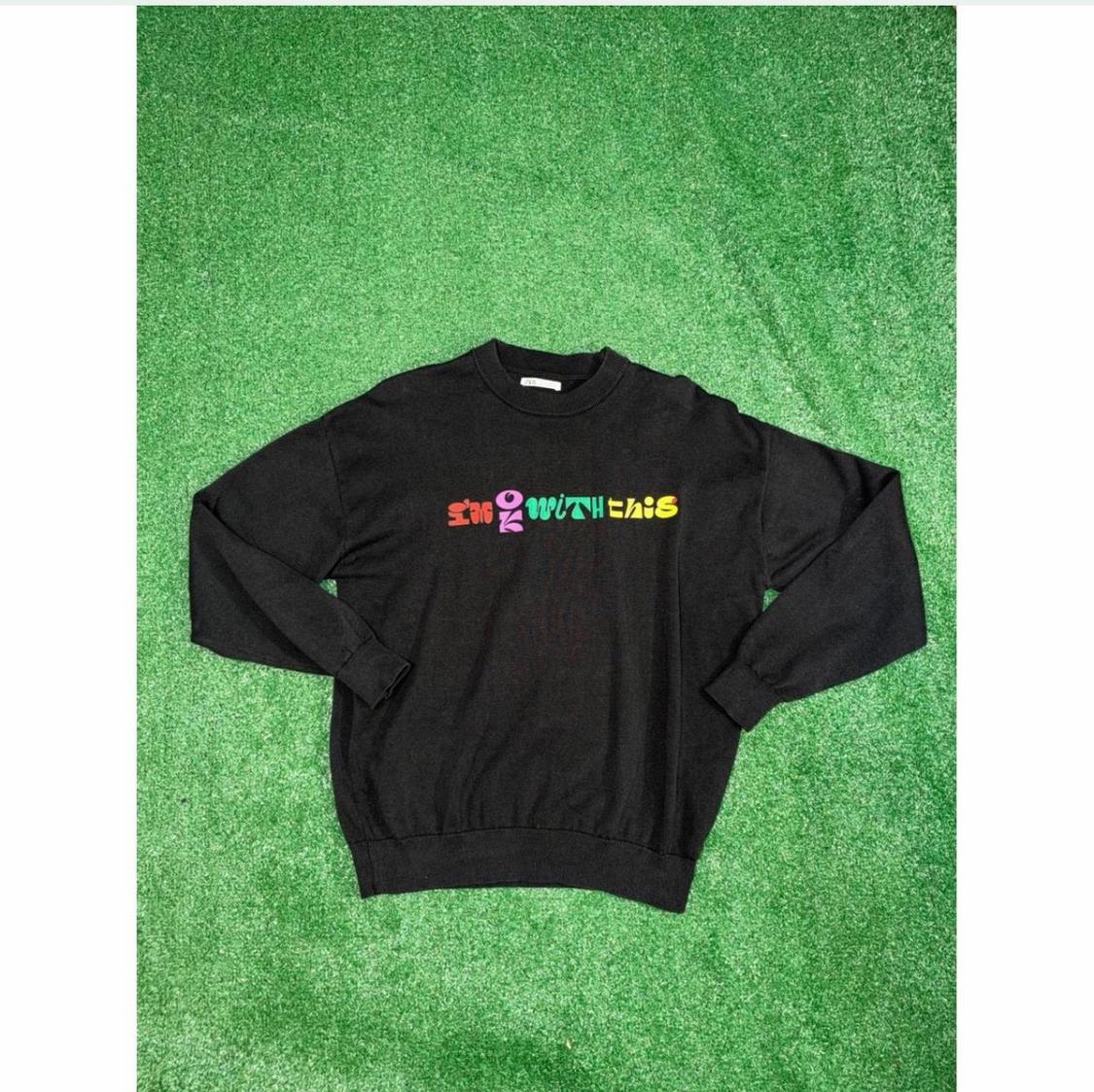 Black hoodie with multicolor text "I'm OK WITH THIS" centered, spread over green grass.
