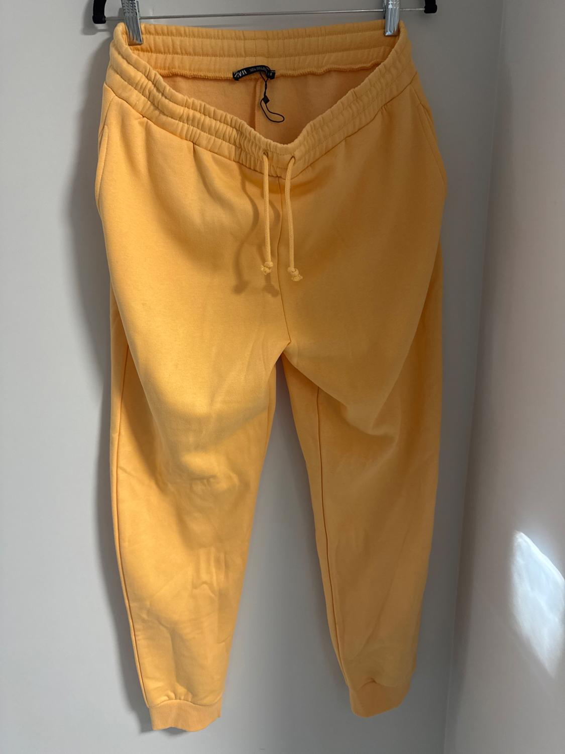 Front view of yellow trousers with elasticated waistband and side pockets.